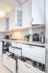 Image showing Luxury modern white kitchen interior with open doors and drawers