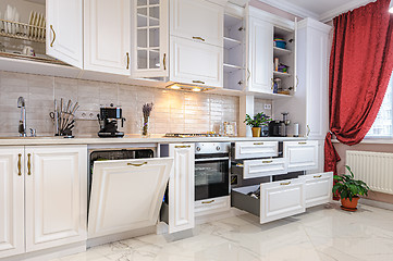 Image showing Luxury modern white kitchen interior with open doors and drawers