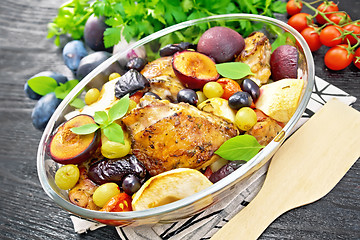 Image showing Chicken with fruits and tomatoes in glass pan on wooden board