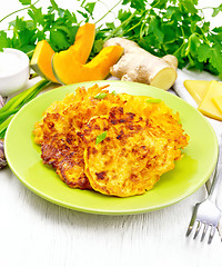 Image showing Pancakes of pumpkin with cheese in green plate on light board