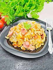 Image showing Cabbage stew with sausages in black plate on board