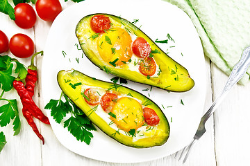 Image showing Scrambled eggs with tomatoes in avocado on wooden board top