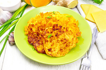 Image showing Pancakes of pumpkin with cheese in green plate on light wooden b