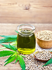 Image showing Oil hemp in jar with flour in bowl on old board