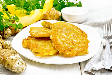 Image showing Pancakes of pumpkin with Jerusalem artichoke in plate on white b