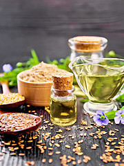 Image showing Oil flaxseed with flour and seeds on dark wooden board