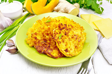 Image showing Pancakes of pumpkin with cheese in green plate on wooden board