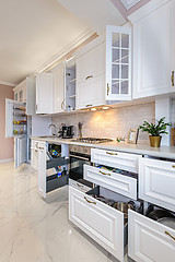 Image showing Luxury modern white kitchen interior with open doors and drawers