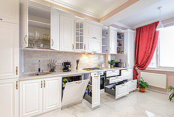 Image showing Luxury modern white kitchen interior with open doors and drawers