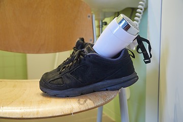 Image showing Drying shoes with a hairdryer