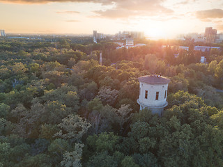 Image showing Aerial view of the drone on the green park with a round tower and the city in the distance at sunset