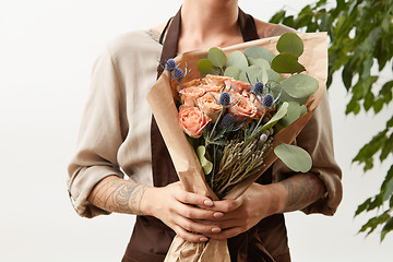 Image showing Woman\'s hands with tattoo hold flower roses bouquet for congratulation on a light background, place for text. Greeting card concept.