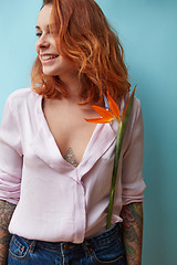 Image showing Young happy woman with tattoo and flower streliutzia on blue bac