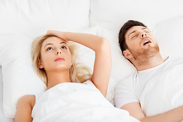 Image showing unhappy woman in bed with snoring sleeping man