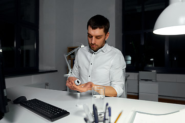 Image showing businessman taking medicine pill at night office