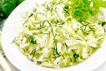 Image showing Salad of cabbage and cucumber in plate on wooden board