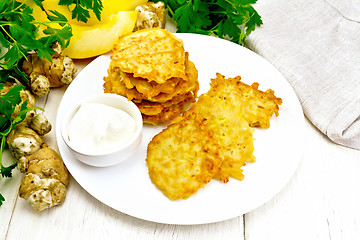 Image showing Pancakes of pumpkin with Jerusalem artichoke in plate on board