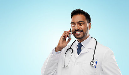 Image showing smiling indian male doctor calling on smartphone