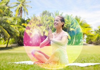 Image showing happy woman meditating in summer park over aura