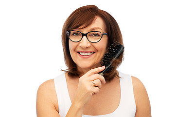 Image showing portrait of senior woman in glasses brushing hair