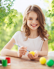 Image showing happy smiling girl coloring easter eggs