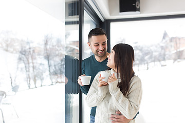 Image showing multiethnic couple enjoying morning coffee by the window