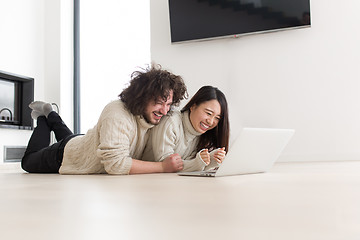 Image showing young multiethnic couple using a laptop on the floor