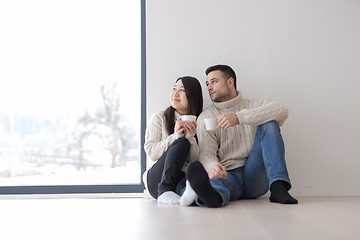 Image showing multiethnic couple enjoying morning coffee by the window