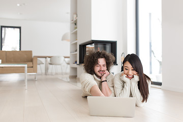 Image showing young multiethnic couple using a laptop on the floor