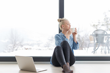 Image showing woman drinking coffee and using laptop at home