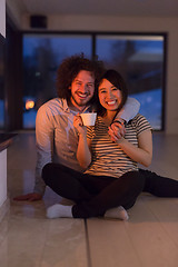 Image showing happy multiethnic couple sitting in front of fireplace