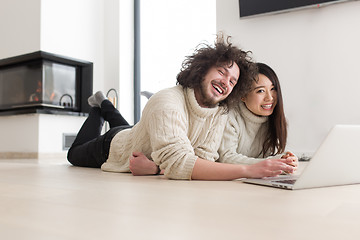 Image showing young multiethnic couple using a laptop on the floor