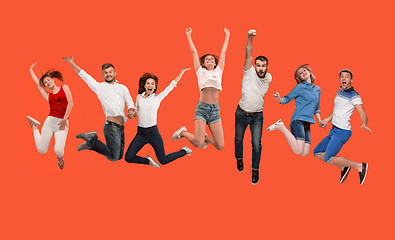 Image showing Freedom in moving. young man and women jumping against red background