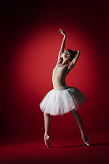 Image showing Ballerina. Young graceful female ballet dancer dancing at red studioskill. Beauty of classic ballet.