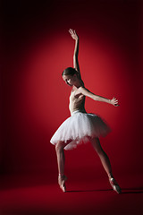 Image showing Ballerina. Young graceful female ballet dancer dancing at red studioskill. Beauty of classic ballet.