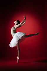 Image showing Ballerina. Young graceful female ballet dancer dancing at red studioskill. Beauty of classic ballet.