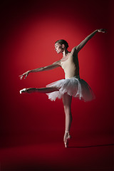 Image showing Ballerina. Young graceful female ballet dancer dancing at red studioskill. Beauty of classic ballet.