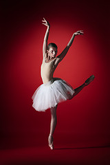 Image showing Ballerina. Young graceful female ballet dancer dancing at red studioskill. Beauty of classic ballet.