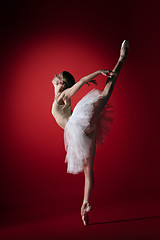 Image showing Ballerina. Young graceful female ballet dancer dancing at red studioskill. Beauty of classic ballet.