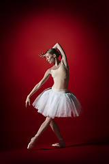 Image showing Ballerina. Young graceful female ballet dancer dancing at red studioskill. Beauty of classic ballet.