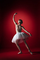 Image showing Ballerina. Young graceful female ballet dancer dancing at red studioskill. Beauty of classic ballet.