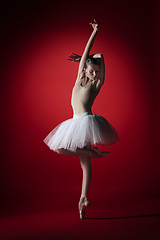 Image showing Ballerina. Young graceful female ballet dancer dancing at red studioskill. Beauty of classic ballet.