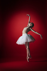 Image showing Ballerina. Young graceful female ballet dancer dancing at red studioskill. Beauty of classic ballet.