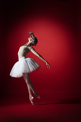 Image showing Ballerina. Young graceful female ballet dancer dancing at red studioskill. Beauty of classic ballet.