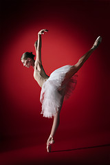 Image showing Ballerina. Young graceful female ballet dancer dancing at red studioskill. Beauty of classic ballet.