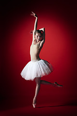 Image showing Ballerina. Young graceful female ballet dancer dancing at red studioskill. Beauty of classic ballet.