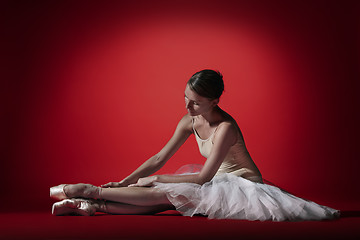 Image showing Ballerina. Young graceful female ballet dancer dancing at red studioskill. Beauty of classic ballet.