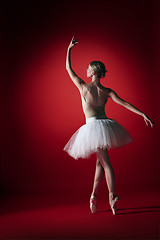 Image showing Ballerina. Young graceful female ballet dancer dancing at red studioskill. Beauty of classic ballet.