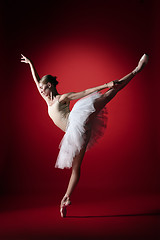 Image showing Ballerina. Young graceful female ballet dancer dancing at red studioskill. Beauty of classic ballet.