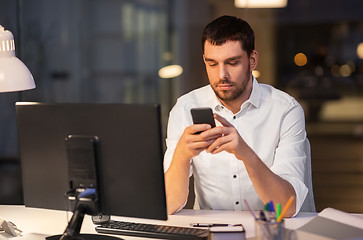 Image showing businessman with smartphone and computer at office